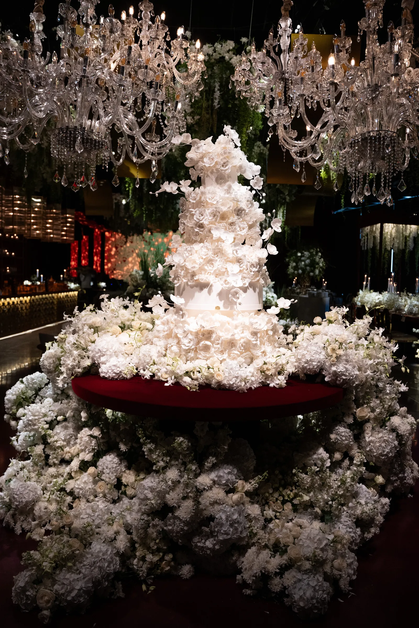 Bolo branco de flores sob dezenas de lustres de cristal